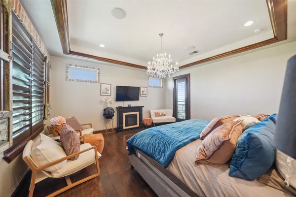 a spacious bedroom with a bed a couch and chandelier