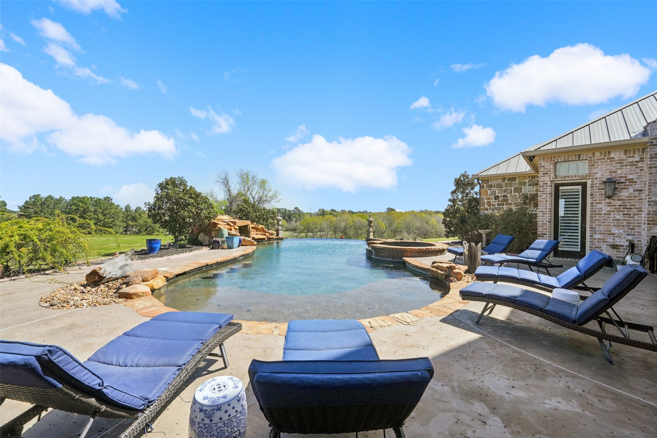 460 Bishop Road Huntsville, TX 77320 - Photo 36 of 50 The patio design includes a spacious tanning ledge and a breathtaking zero-edge pool at the back. Enhancing the outdoor experience, landscape speakers provide ambient sound, while a hot tub offers additional relaxation.