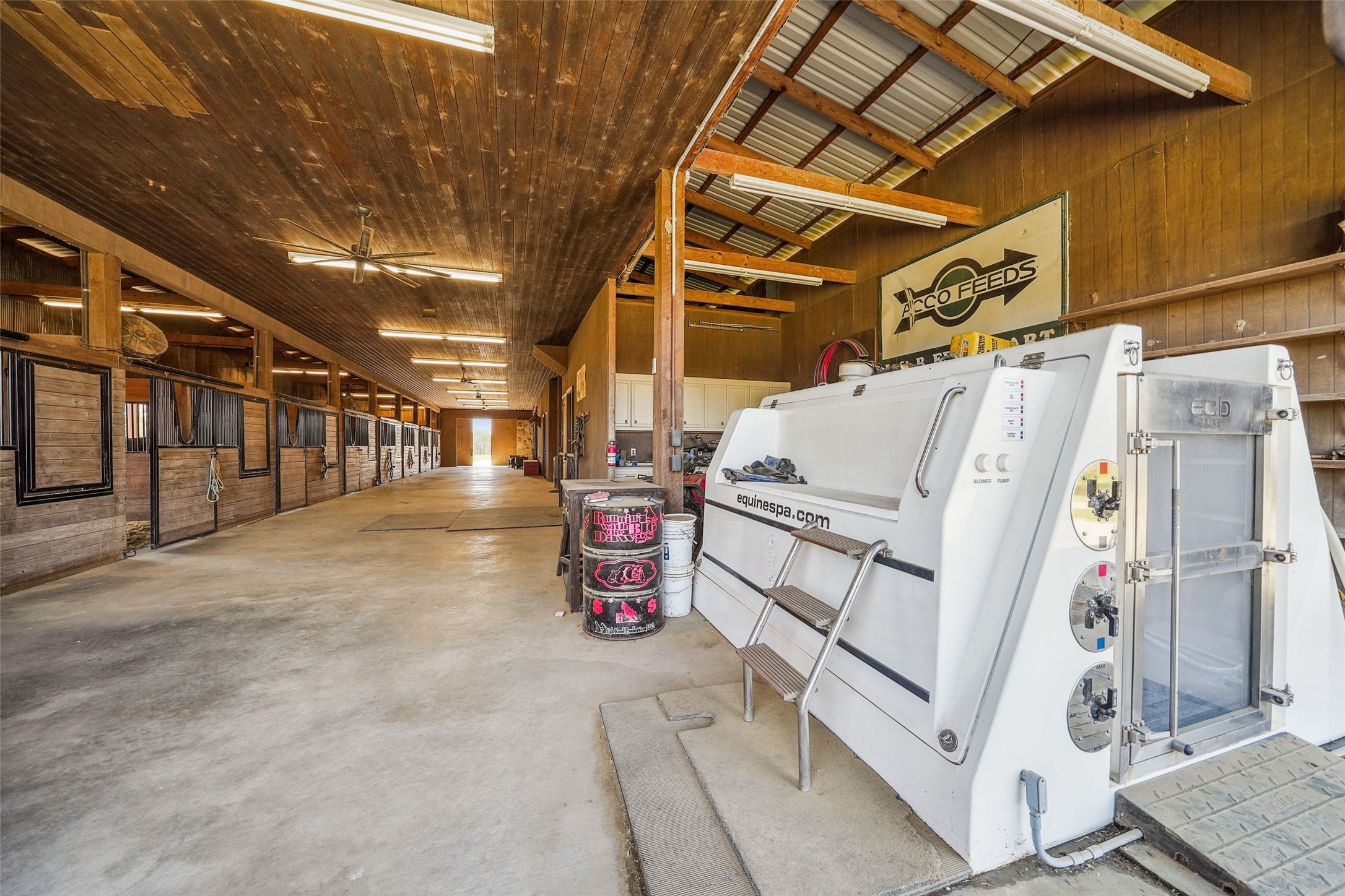 460 Bishop Road Huntsville, TX 77320 - Photo 41 of 50 This top-tier equestrian facility features an advanced equine spa for therapy and recovery, promoting circulation and reducing inflammation available for additional purchase. The barn includes a stone interior wash rack with a tie rack, a climate-controlled feed and tack room with a refrigerator and stackable washer/dryer, and built-in cabinetry. An indoor hay room provides convenient storage, with ample parking for a tractor and equipment.