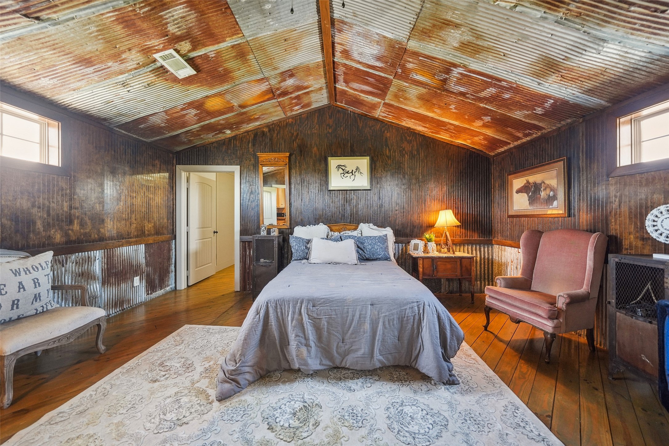 460 Bishop Road Huntsville, TX 77320 - Photo 46 of 50 This inviting guesthouse bedroom blends rustic charm with modern comfort. Featuring warm wood floors, tongue and groove ceilings, and unique rustic tin accents, the space exudes character. Soft natural light filters through the windows, highlighting the cozy ambiance.