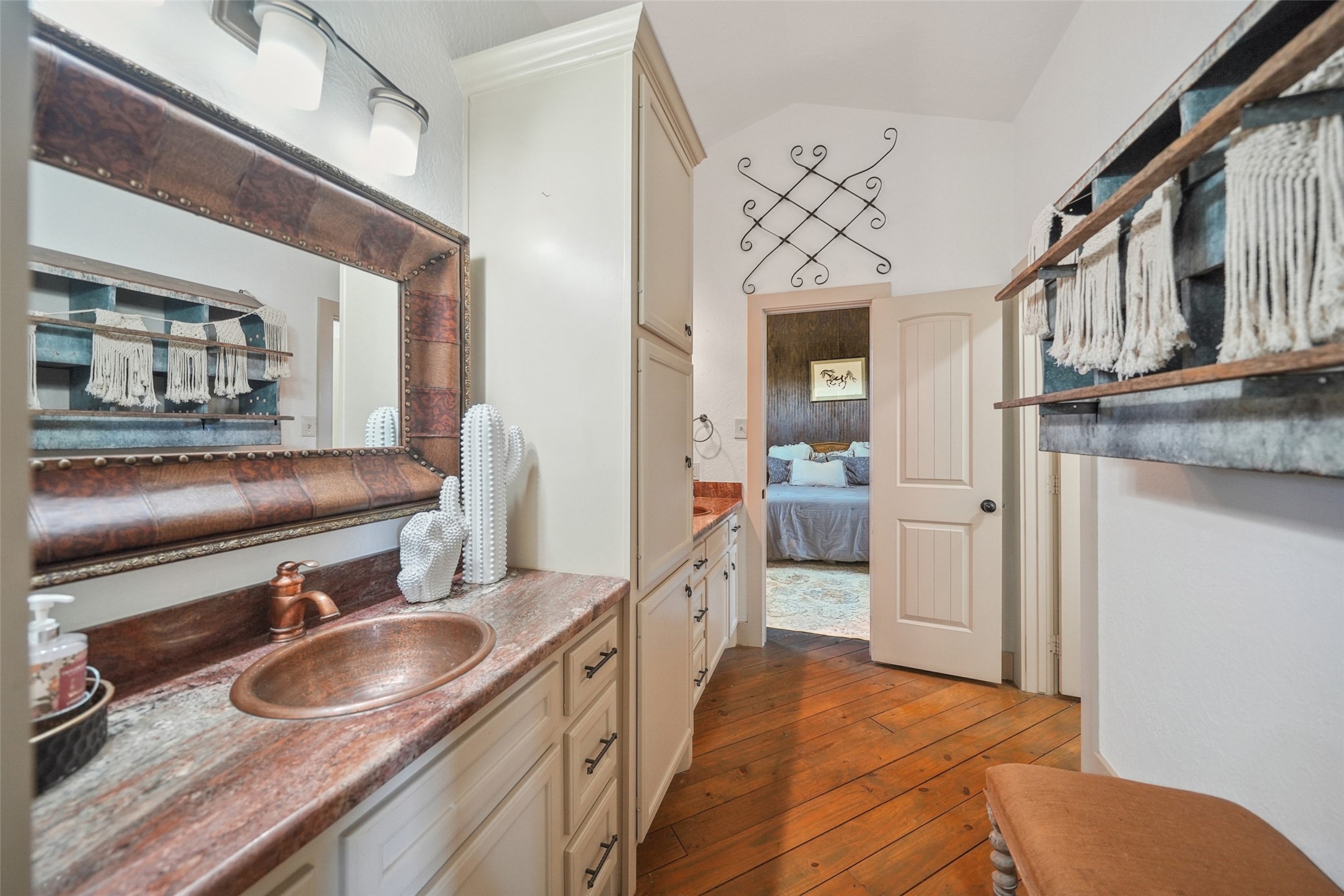 460 Bishop Road Huntsville, TX 77320 - Photo 47 of 50 Charming guesthouse bathroom with rustic elegance. Features rich wood floors, a copper sink, and custom cabinetry. Thoughtful details like the leather-trimmed mirror and open shelving add warmth and character.