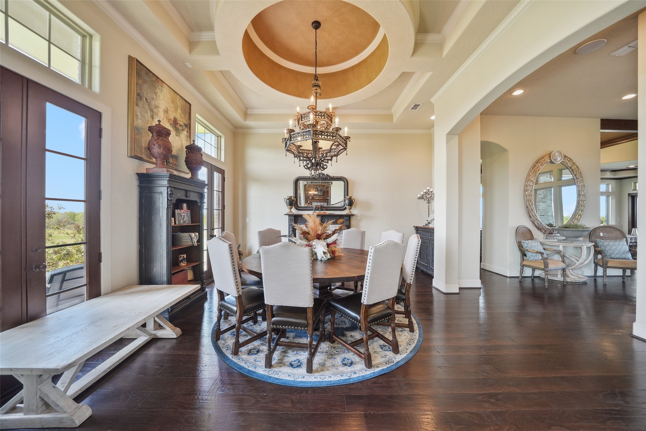 460 Bishop Road Huntsville, TX 77320 - Photo 5 of 50 The formal dining room features two sets of elegant French doors open onto the porch, while custom ceiling framing, intricate trim, and detailed paintwork add a touch of sophistication. A charming fireplace featuring an antique brick hearth and mantel serves as the focal point of the room.