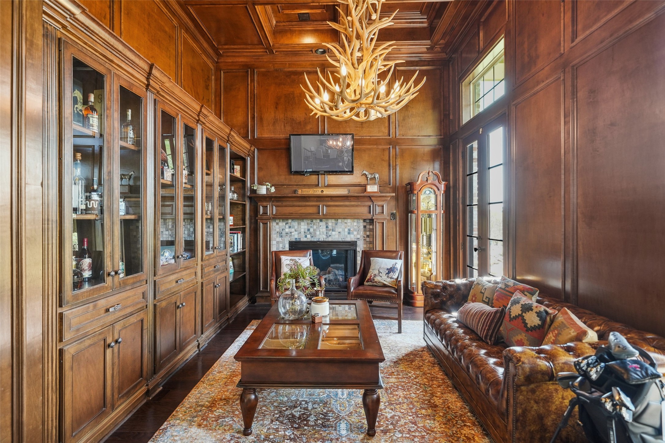460 Bishop Road Huntsville, TX 77320 - Photo 6 of 50 This elegant space features custom-stained trim, maple-wrapped walls, and a uniquely framed ceiling. Two sets of French doors open to the porch, while a hidden safe room, secured by a vault door, includes concrete walls, built-in gun racks, and ventilation. A fireplace adds warmth, and a staircase leads to an additional study with built-in cabinetry.