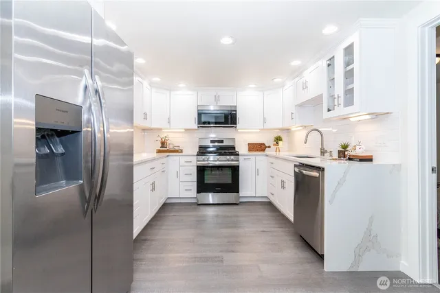 a kitchen with granite countertop a refrigerator oven a sink and cabinets