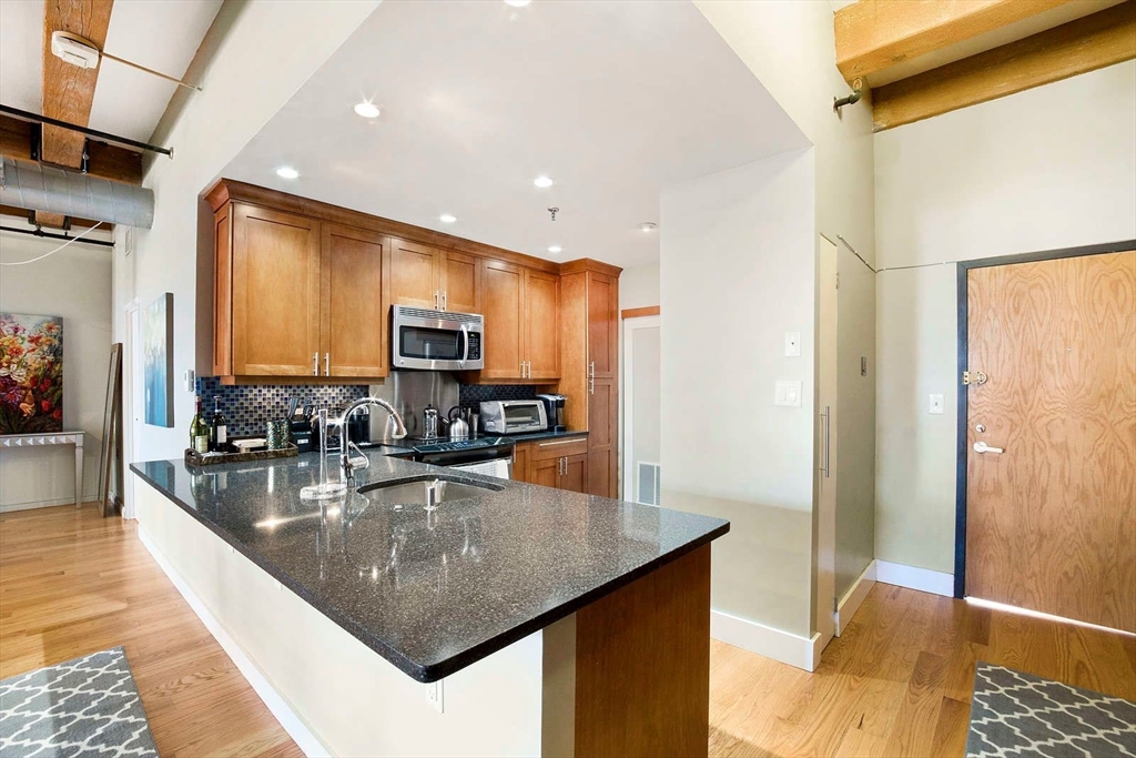 33 Sleeper Street, Unit 508 Boston, MA 02210 - Photo 5 of 11 a kitchen with stainless steel appliances granite countertop a sink a stove and a refrigerator