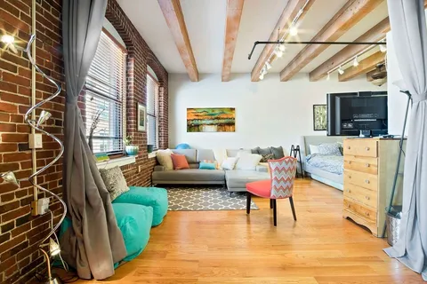 a living room with furniture a flat screen tv and a floor to ceiling window