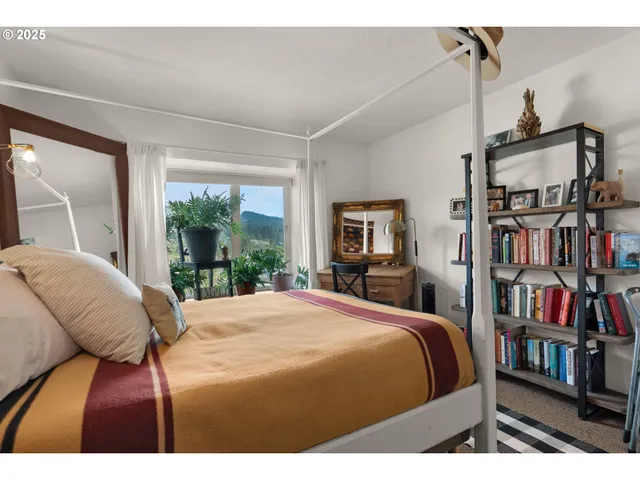 a bedroom with a bed a large window and a book shelf