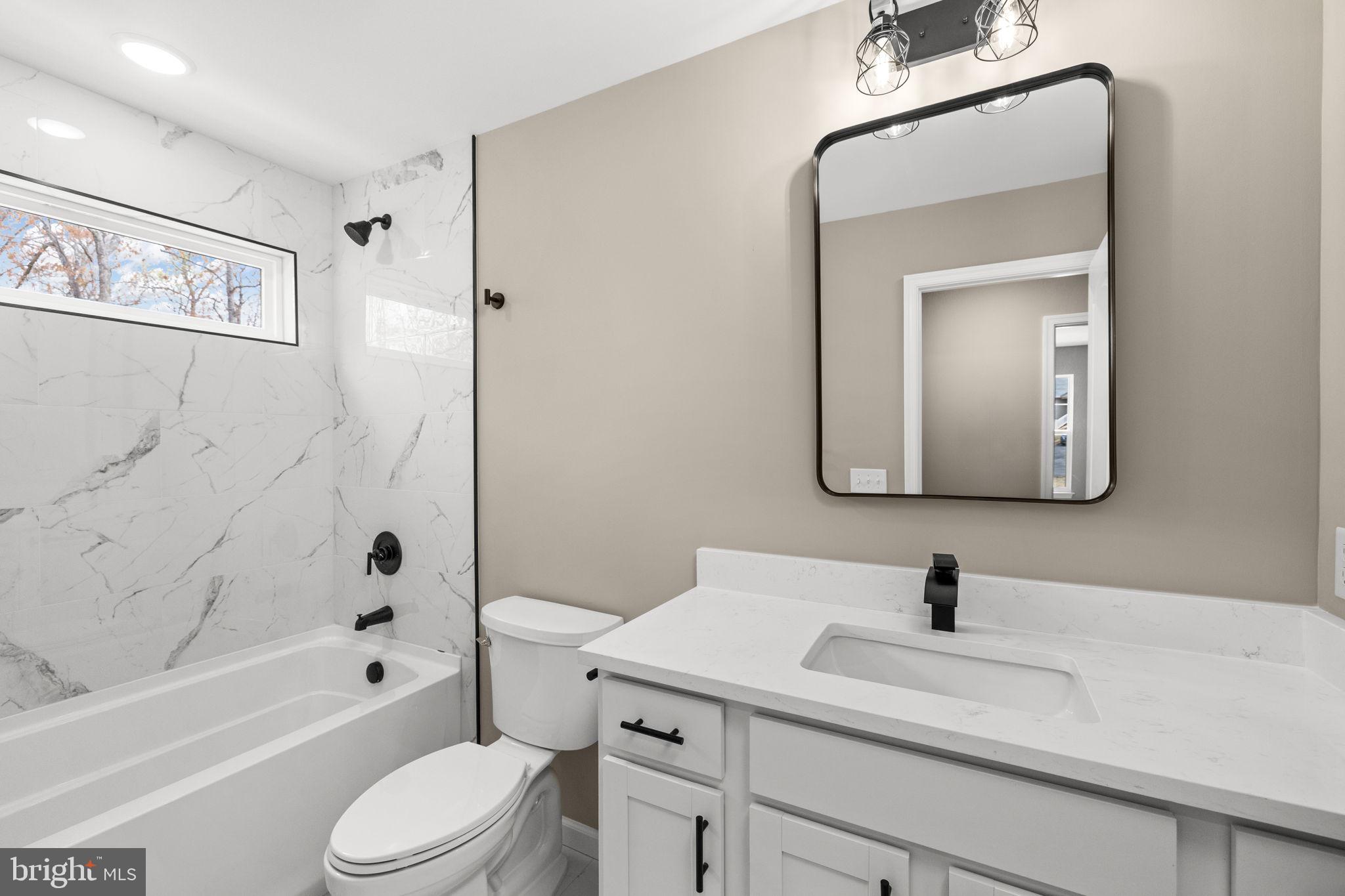 12413 Toll House Road Spotsylvania, VA 22551 - Photo 43 of 68 a bathroom with a toilet a sink a mirror a bathtub and shower