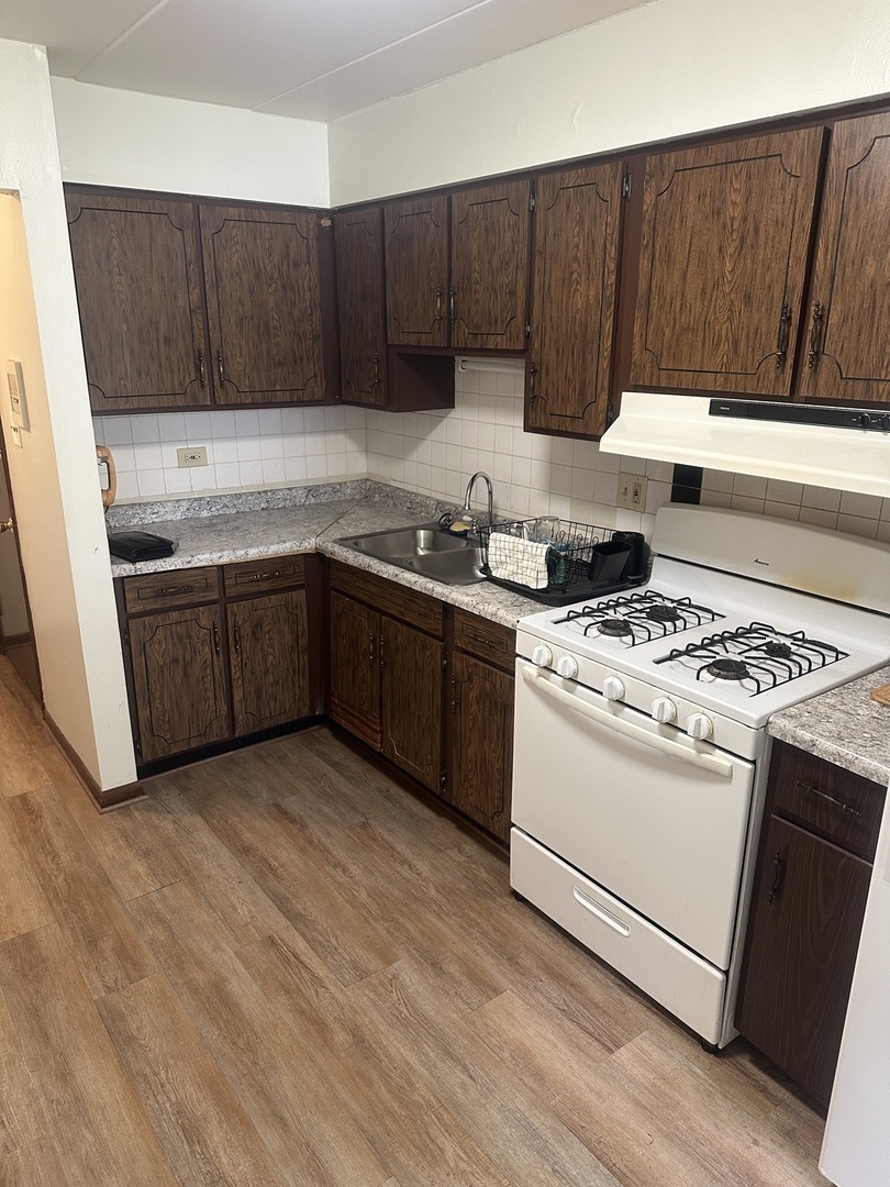 18550 Torrence Avenue, Unit 4 Lansing, IL 60438 - Photo 13 of 14 a kitchen with granite countertop wooden cabinets and white appliances