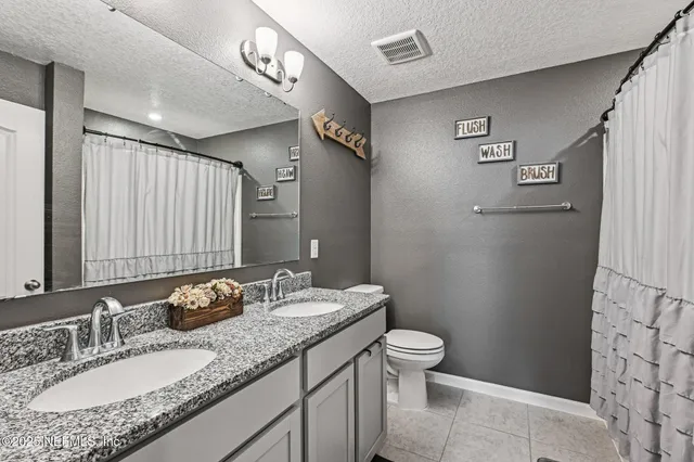 a bathroom with a granite countertop sink a toilet and a mirror