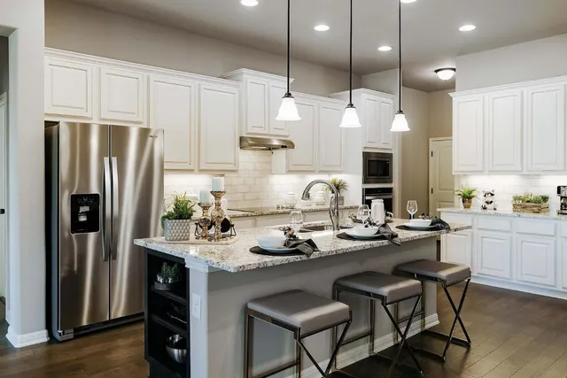 a kitchen with granite countertop a sink cabinets stainless steel appliances and dining table