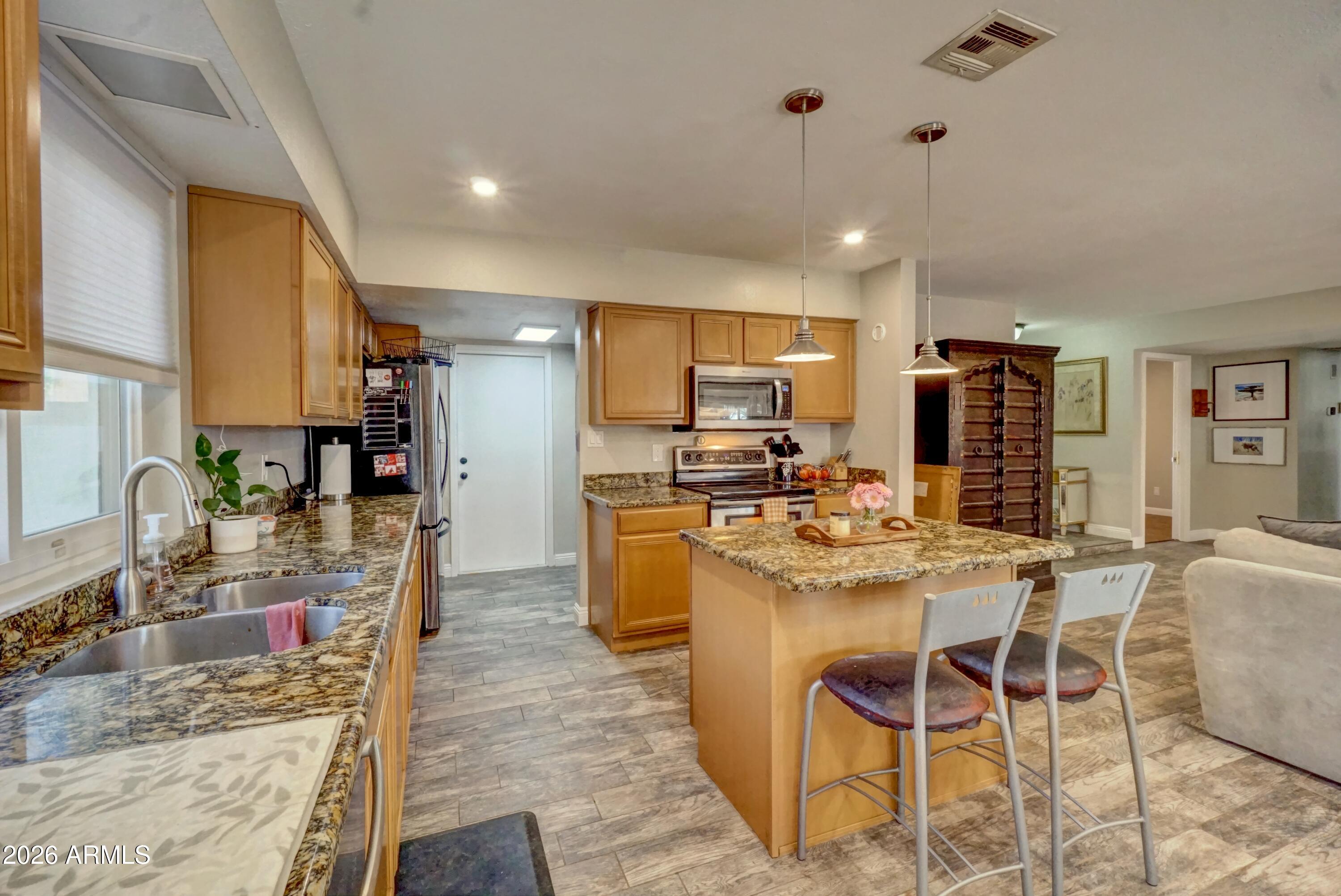2749 East Sylvia Street Phoenix, AZ 85032 - Photo 13 of 44 a kitchen with stainless steel appliances kitchen island granite countertop a sink and cabinets