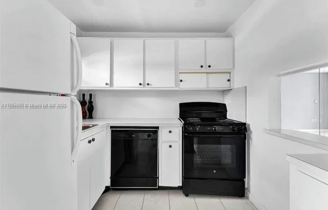 a kitchen with white cabinets and black appliances