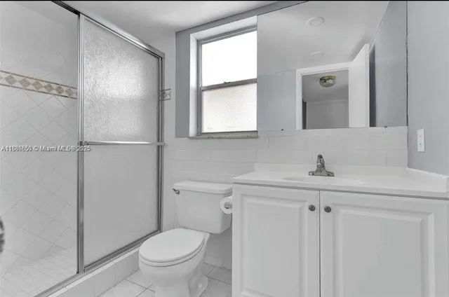 a bathroom with a toilet a sink a mirror a window and vanity