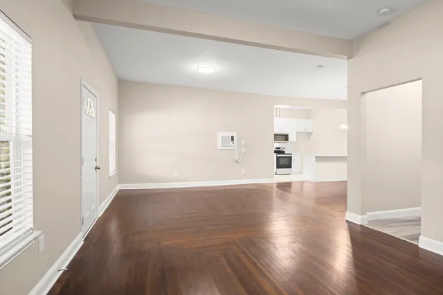 an empty room with wooden floor and windows