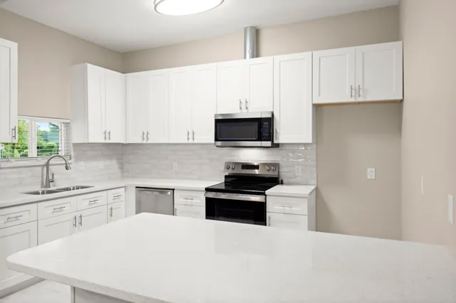 a kitchen with white cabinets and appliances