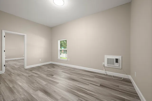 an empty room with wooden floor and windows