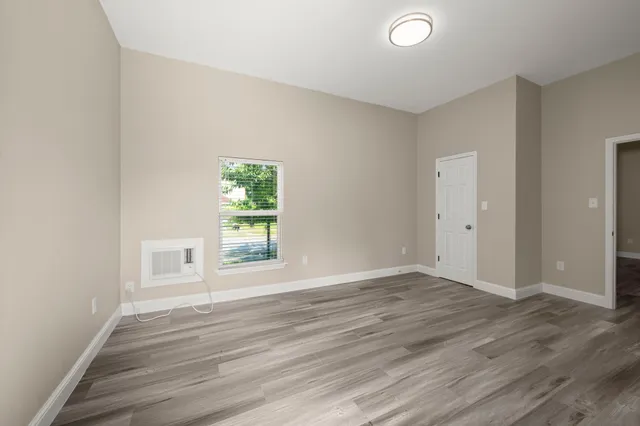 a view of an empty room with wooden floor and a window