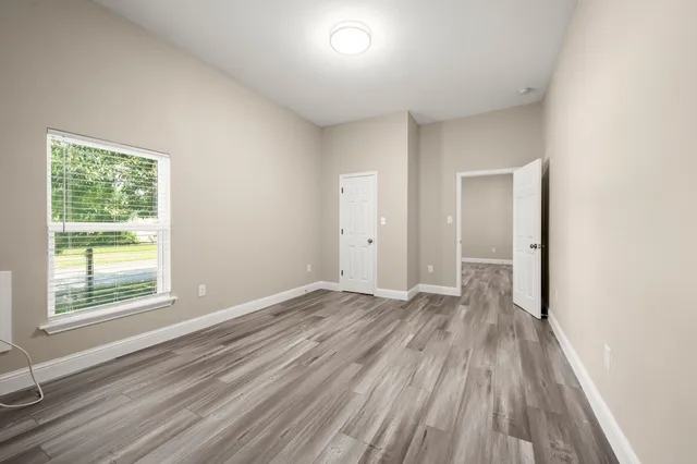 a view of an empty room with wooden floor and a window