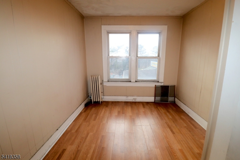413 Lyons Avenue, Unit 2L Newark, NJ 07112 - Photo 11 of 15 an empty room with wooden floor and windows