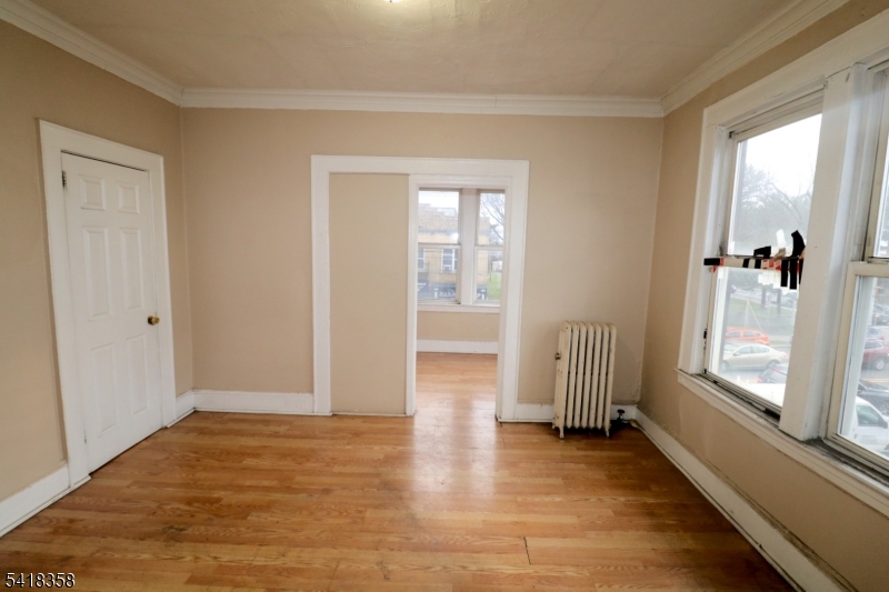 413 Lyons Avenue, Unit 2L Newark, NJ 07112 - Photo 4 of 15 an empty room with wooden floor and windows