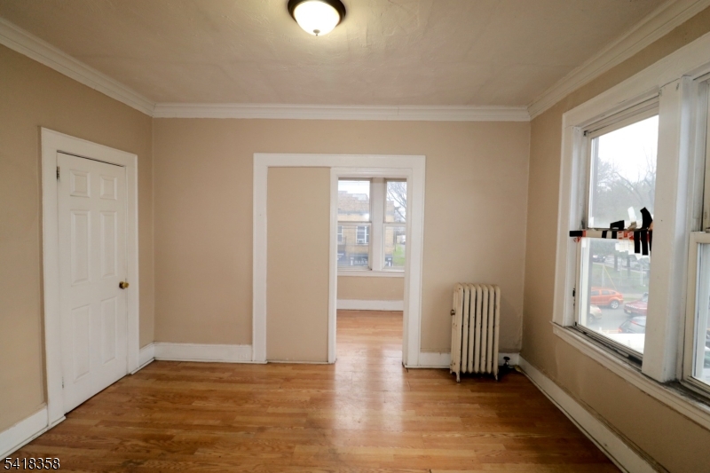 413 Lyons Avenue, Unit 2L Newark, NJ 07112 - Photo 6 of 15 an empty room with wooden floor and a window