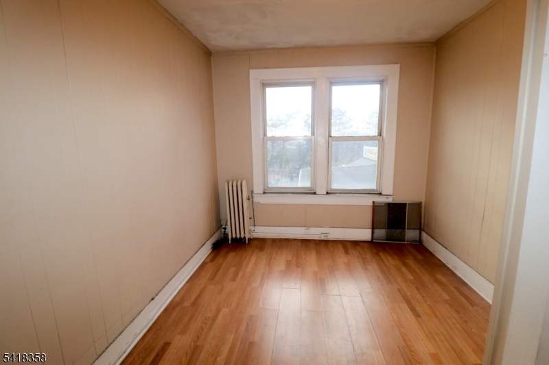 413 Lyons Avenue, Unit 2L Newark, NJ 07112 - Photo 10 of 15 an empty room with wooden floor and windows