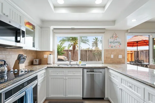 a kitchen with granite countertop stainless steel appliances a sink stove and cabinets