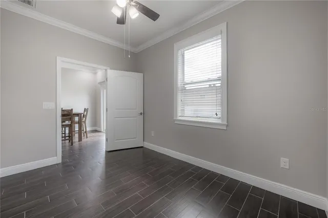 a view of empty room with wooden floor fan and window