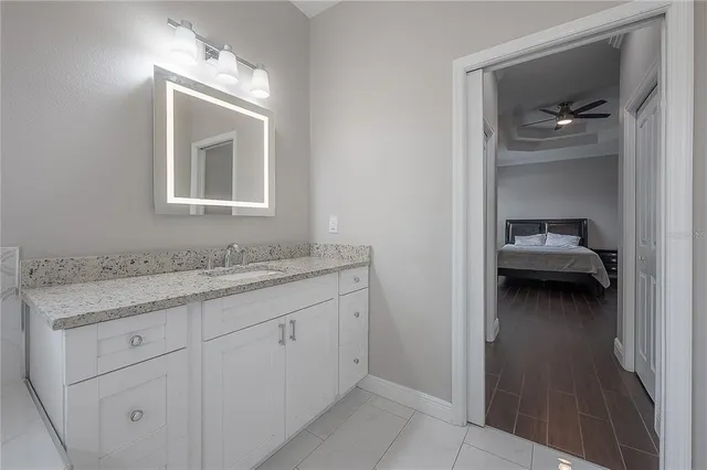 a en suite bathroom with a granite countertop sink and a mirror