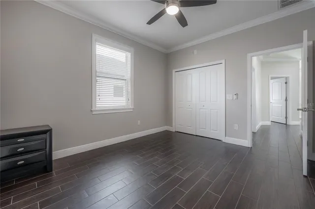 an empty room with wooden floor cabinet and windows