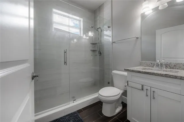 a bathroom with a granite countertop sink toilet and shower