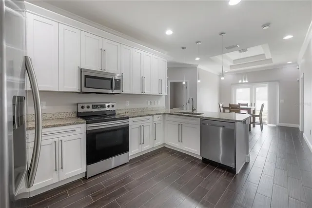 a kitchen with stainless steel appliances granite countertop a stove a sink and a microwave