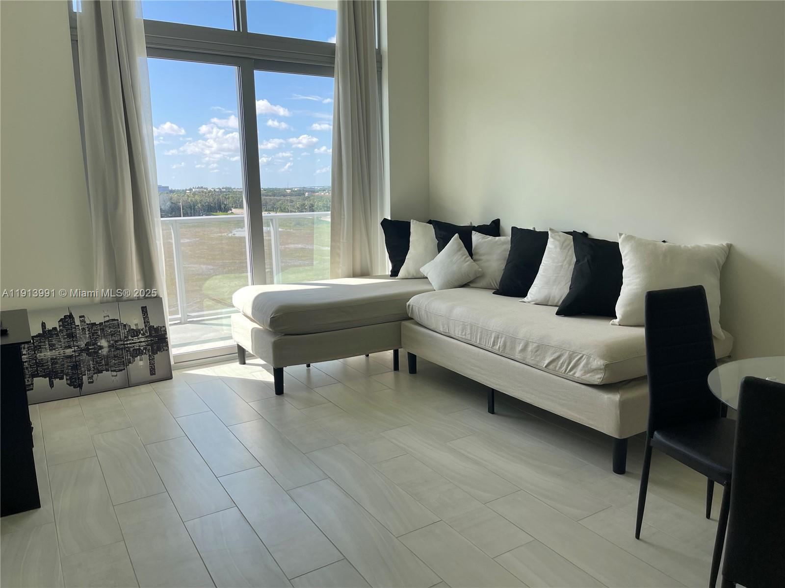 2000 Metropica Way, Unit 605 Sunrise, FL 33323 - Photo 21 of 24 a spacious bedroom with a bed a couch and a large window