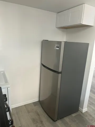a view of a refrigerator in kitchen and an empty room