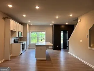 a living room with stainless steel appliances furniture refrigerator and a wooden floor