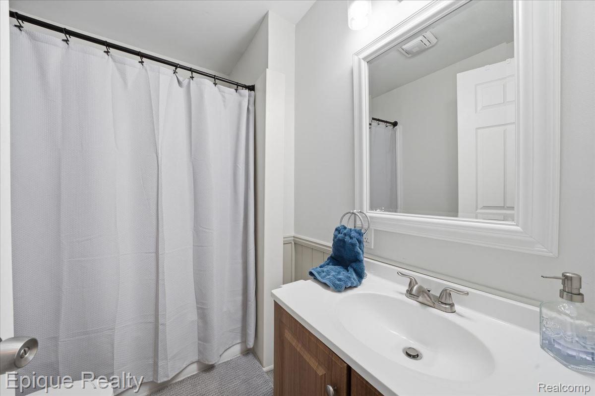 12272 East Mt Morris Road Davison, MI 48423 - Photo 20 of 39 Bathroom featuring a wood-finish vanity with a white countertop and integrated sink, framed mirror, and a shower with a privacy curtain