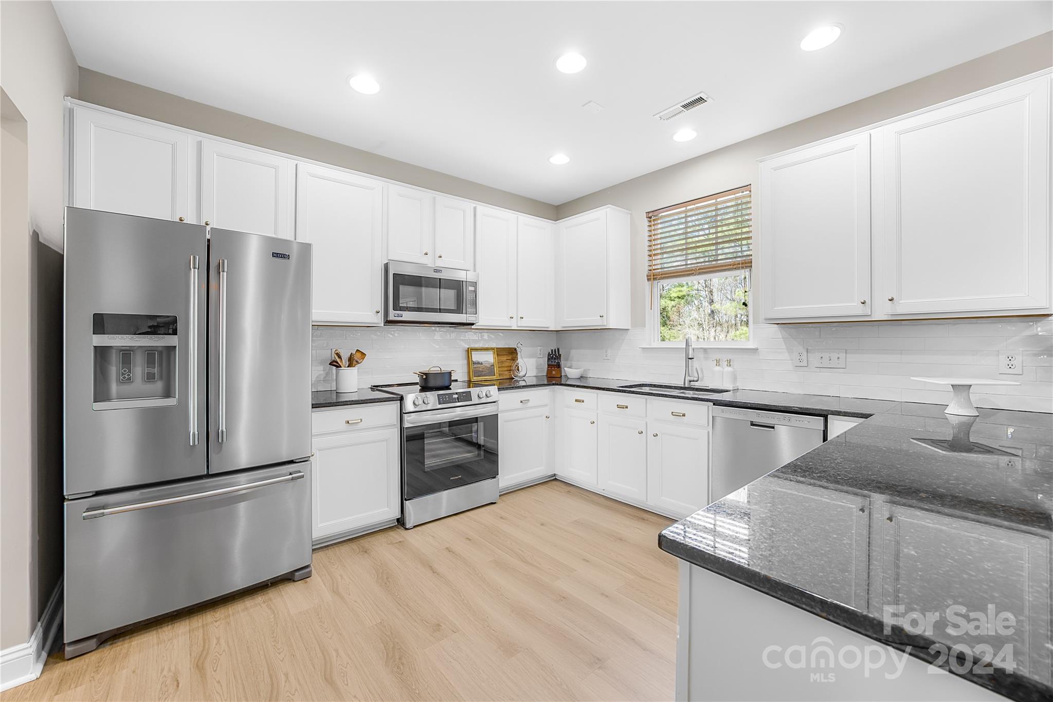 1003 Sipes Place Indian Trail, NC 28079 - Photo 20 of 45 a kitchen with granite countertop a refrigerator stove and microwave