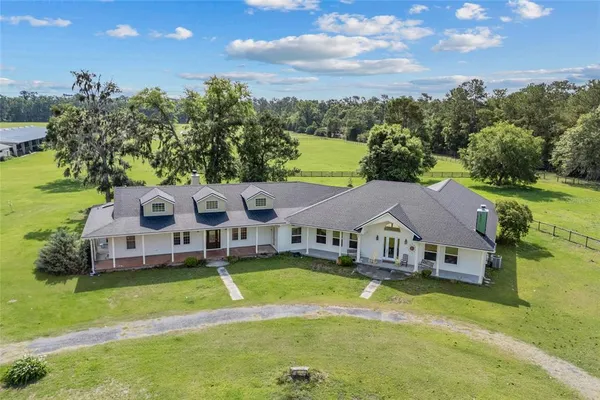 a aerial view of a house with swimming pool and large trees