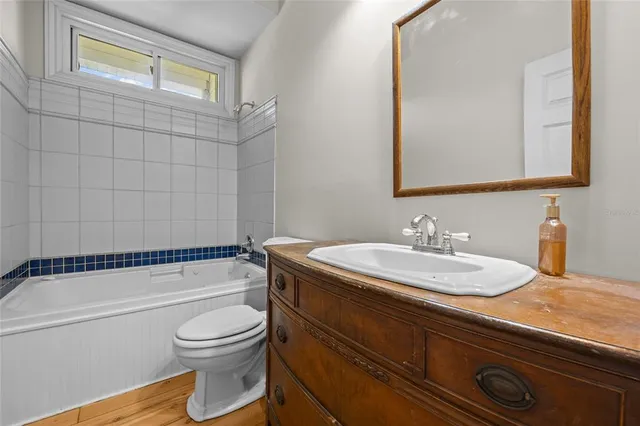 a bathroom with a granite countertop bathtub sink vanity mirror and toilet