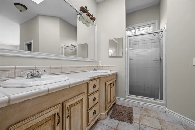 a spacious bathroom with a granite countertop sink a mirror and shower