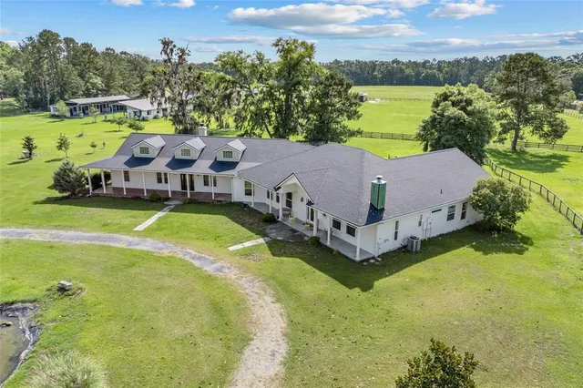 a view of a house with a big yard and large trees