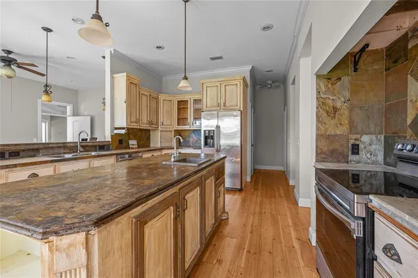 a kitchen with stainless steel appliances granite countertop a sink a stove and a wooden floors