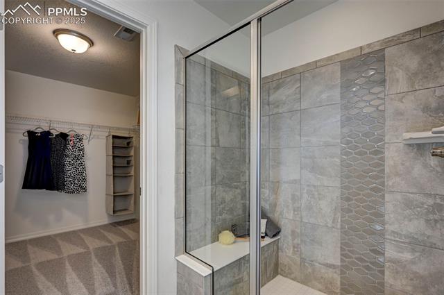 5057 Truscott Road Colorado Springs, CO 80925 - Photo 25 of 48 Bathroom featuring a shower with shower door and a textured ceiling