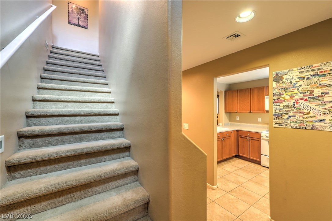 9068 West Alluring Avenue Las Vegas, NV 89149 - Photo 11 of 23 This interior features a well-maintained staircase and an inviting kitchen with natural wood cabinetry.