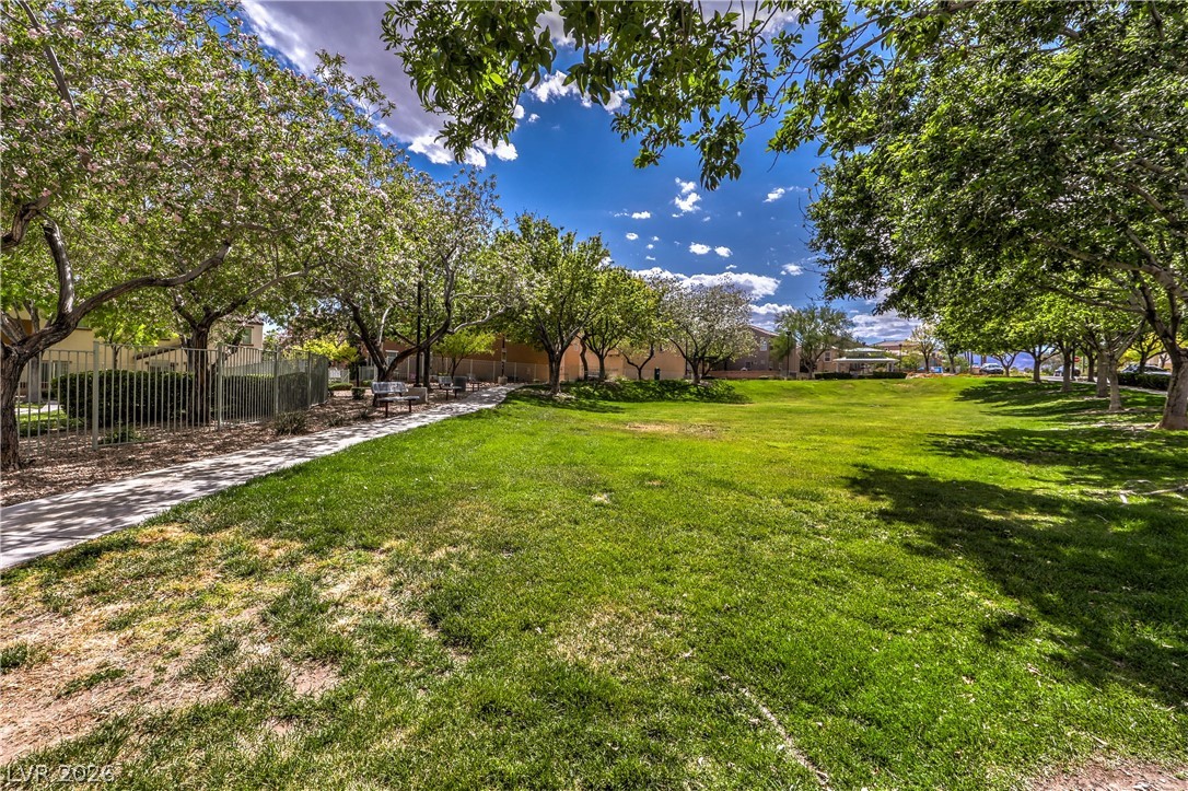 9068 West Alluring Avenue Las Vegas, NV 89149 - Photo 20 of 23 A vibrant green park path with mature trees under a brilliant blue sky.