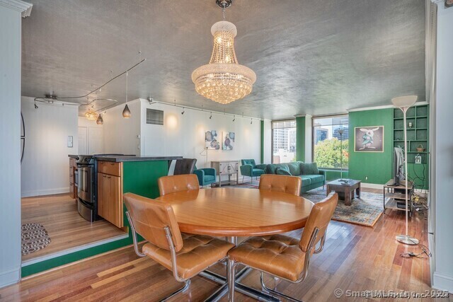 1 Gold Street, Unit 11E Hartford, CT 06103 - Photo 9 of 25 a dining room with wooden floor a chandelier a wooden table and chairs