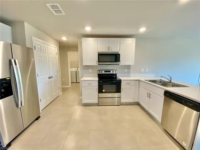 a large kitchen with a sink stainless steel appliances and cabinets
