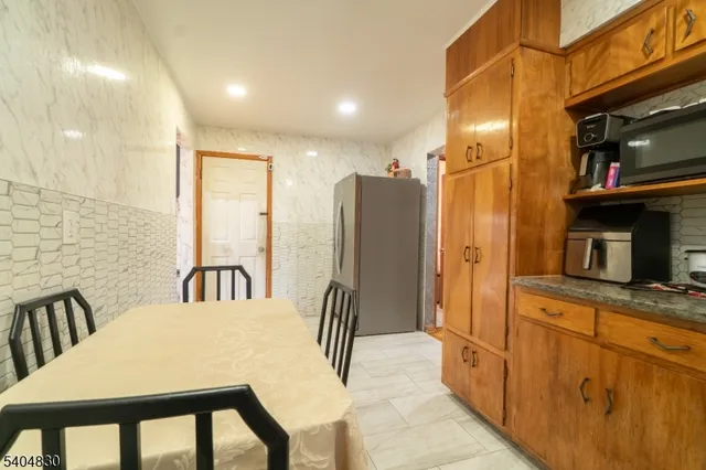 a kitchen with stainless steel appliances granite countertop a refrigerator a stove top oven and a dining table with wooden floor