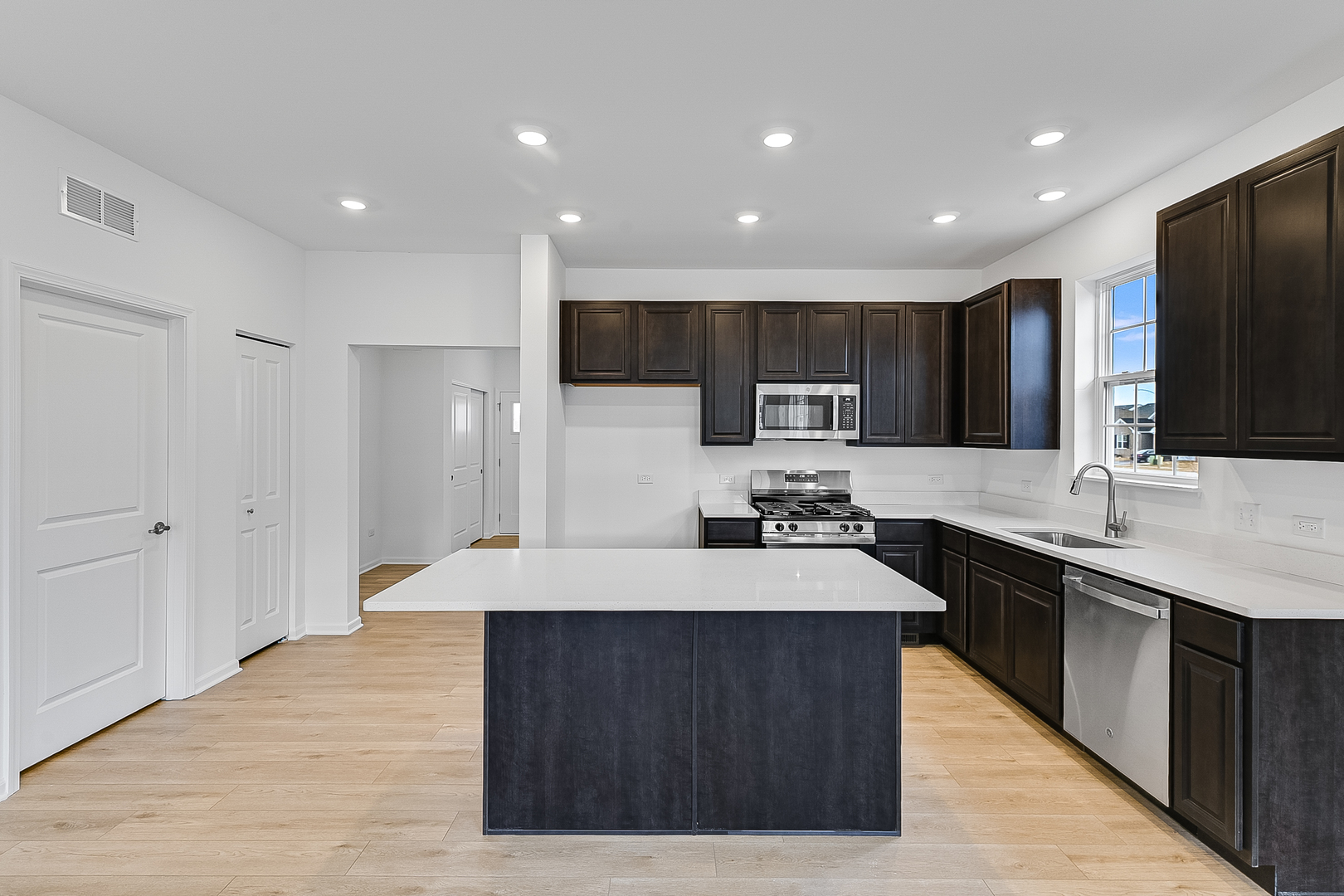 14905 South Mccarthy Circle Plainfield, IL 60544 - Photo 5 of 13 a large kitchen with stainless steel appliances kitchen island a sink dishwasher a stove and a refrigerator with wooden floor